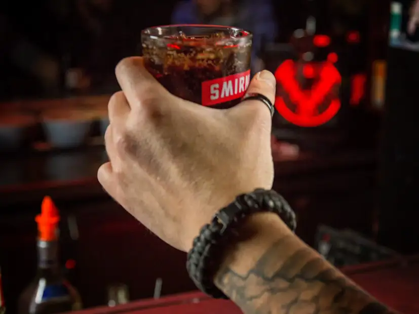 Nahaufnahme Männerhand hält vor Bar Glas Smirnoff mit Cola